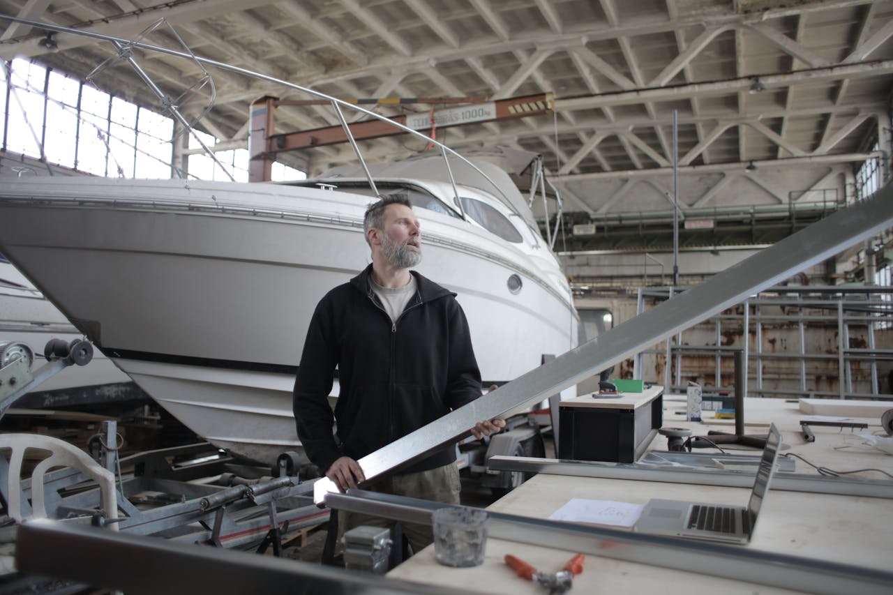 serious adult worker examining metal part near boat in workshop 3823440.jpeg